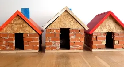 Ensemble de 3 petites maisons en brique et toits en bois. L'atelier "Maison des 3 petits cochons" est proposé par Les Inventeurs.