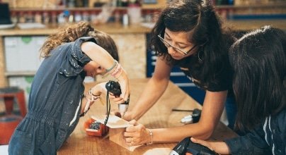 Un enfant fabrique un objet en bois au cours d'un atelier menuiserie