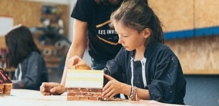 un enfant fabrique la maison des trois petits cochons en brique