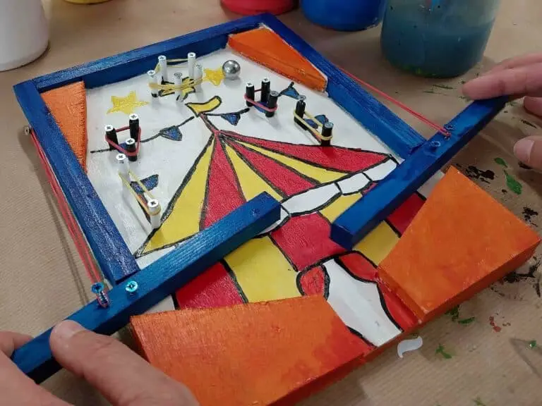 Un enfant joue avec un flipper en bois peint en couleurs vives
