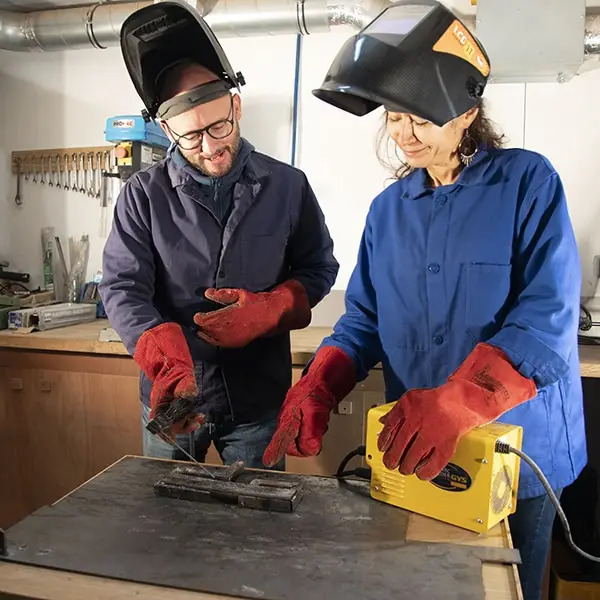 Deux personnes qui portent des masques de protection travaillent dans un atelier métal