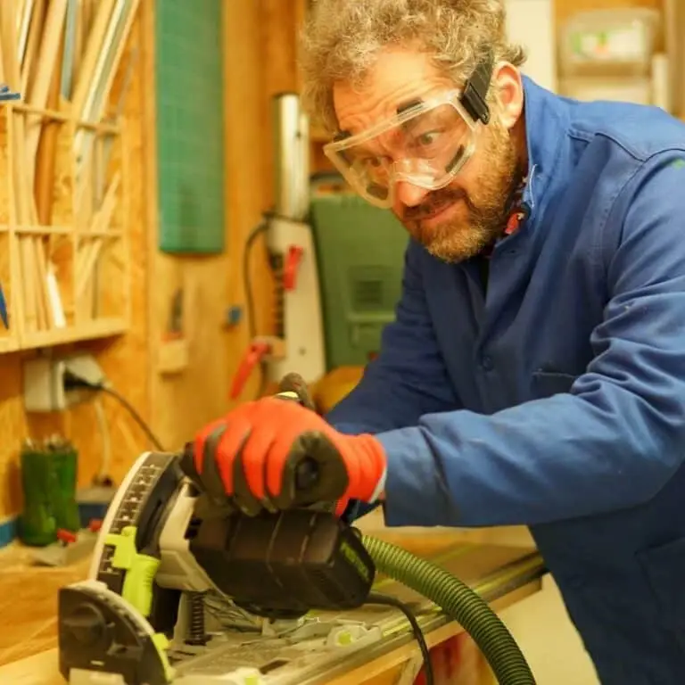 un homme portant des lunettes de sécurité manipule une scie plongeante