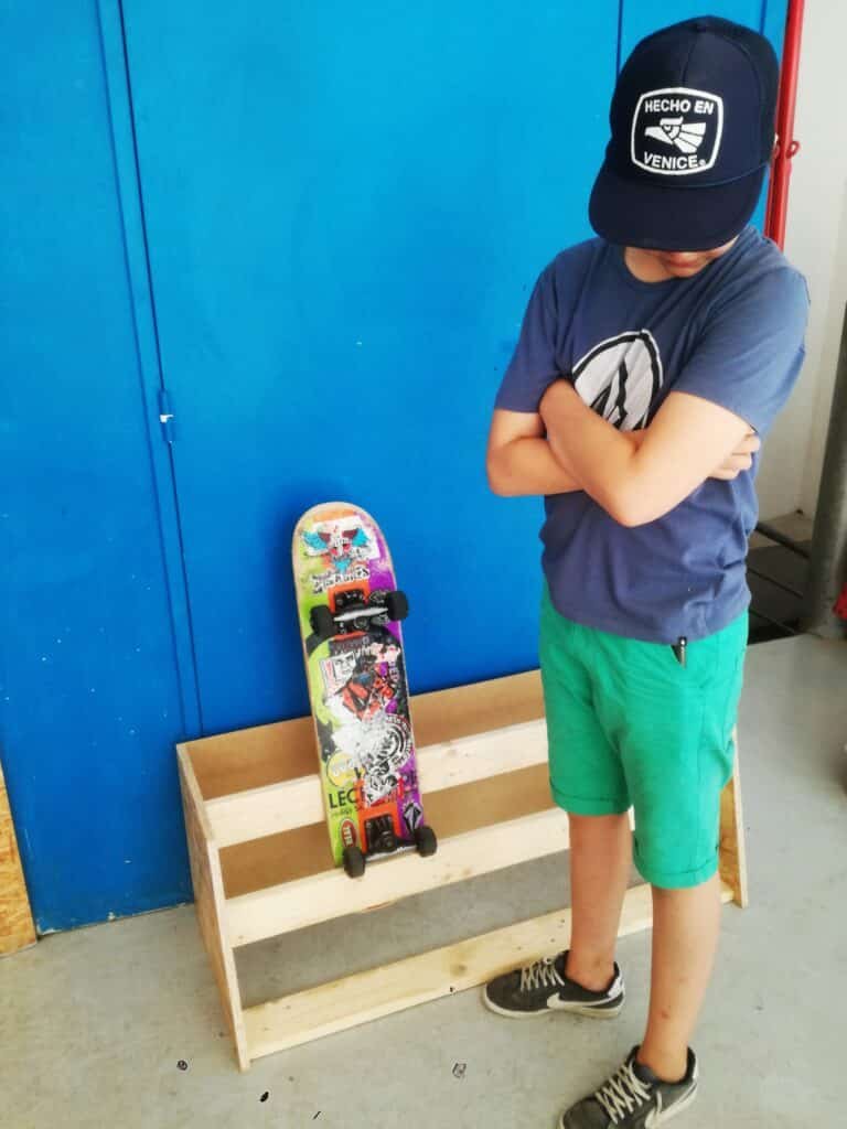 Un ado présente un meuble en bois qu'il a fabriqué