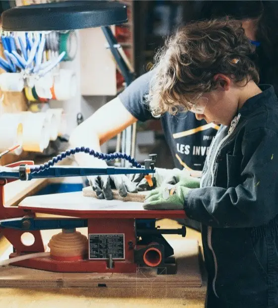 Un enfant utilise une scie à chantourner, menuiserie pour enfants