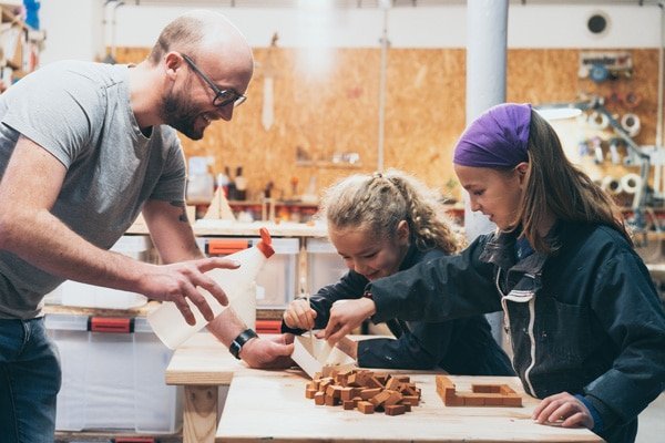 2 enfants fabriquent une maison de briques avec l'aide d'un animateur